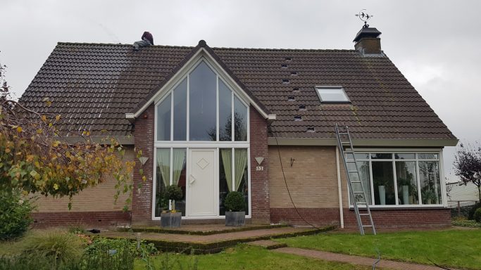 Moderne woning met grote ramen, lichtgekleurde gevel en een tuin met bomen.