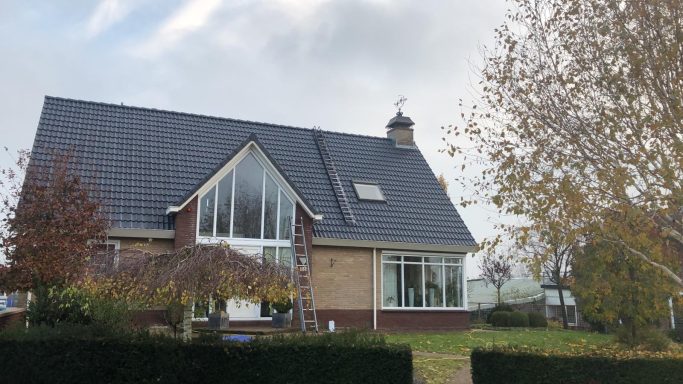 Moderne woning met een schuin dak, grote ramen en een tuin met bomen.